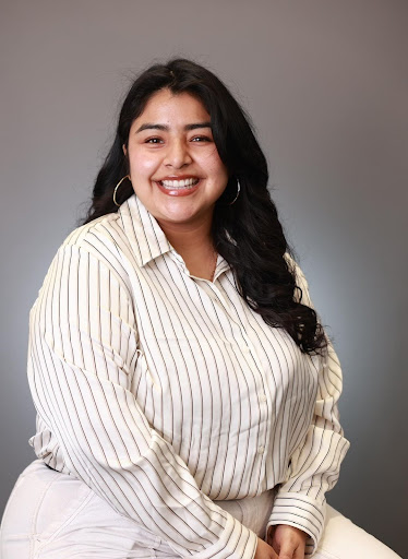 Lesley Aguirre of UC Irvine. She is against a grey background wearing a white striped shirt.
